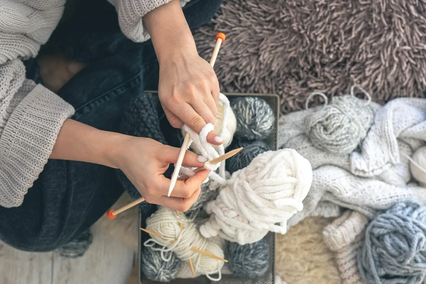 Junge Frau strickt zu Hause einen warmen Pullover, von oben gesehen.